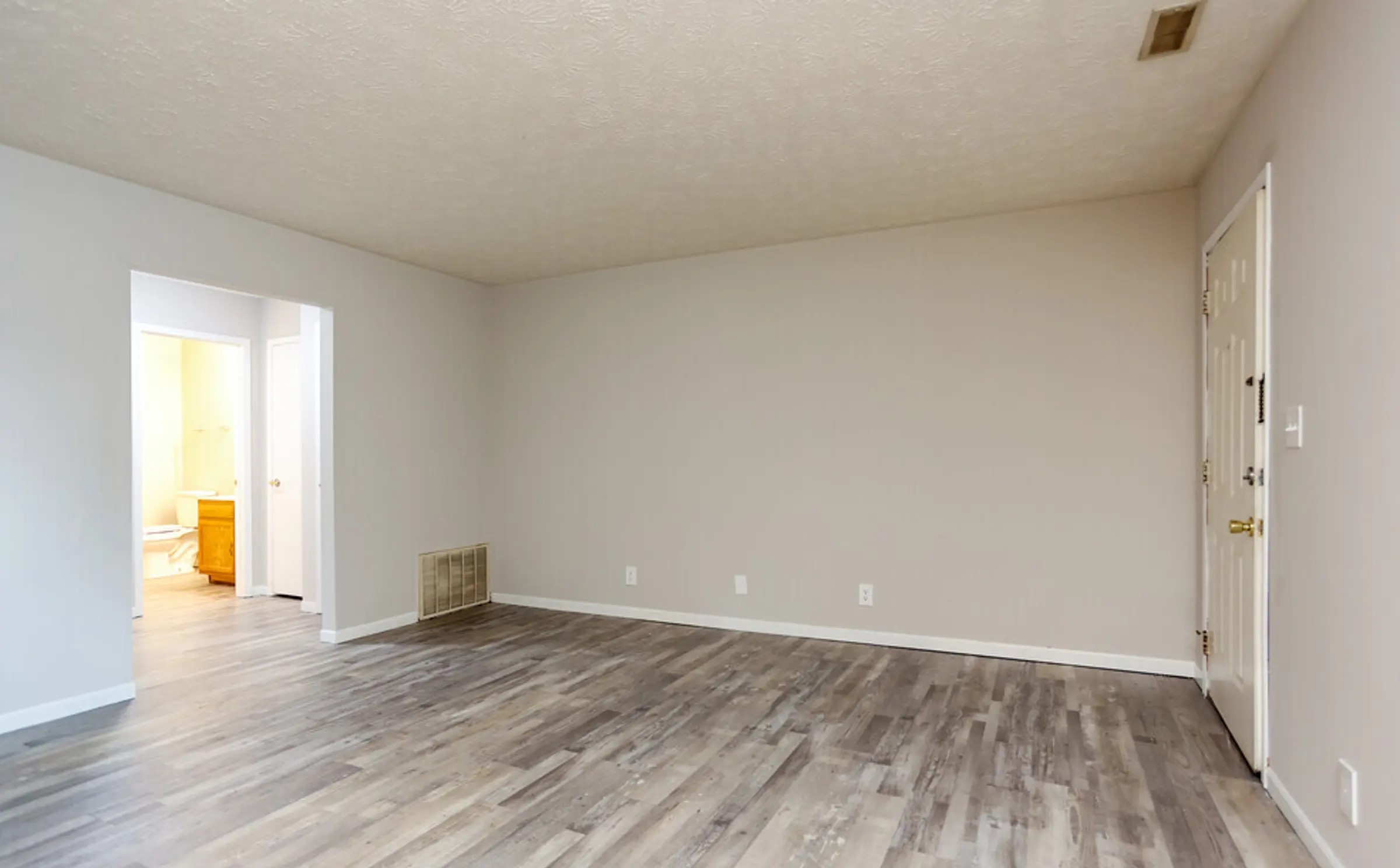 A bright, open living area, in our 1 bedroom apartment, featuring beautiful wood-style flooring and neutral walls, making it easy to personalize and decorate. The layout offers seamless flow between spaces, ideal for both relaxation and entertaining. The adjacent hallway leads to additional rooms, creating a warm and inviting environment for everyday living.