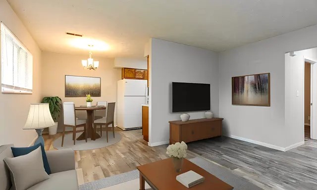 A beautifully staged, 1 bedroom apartment living space that showcases the potential of open-concept living. The cozy living area, complemented by a stylish sofa and warm décor, seamlessly transitions into a quaint dining area adjacent to the kitchen. Natural light floods the room, highlighting the attractive wood-style flooring and neutral color scheme. Perfect for entertaining guests or enjoying quiet nights at home, this space is designed for comfort and versatility.