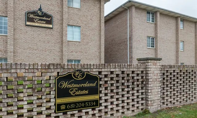 A welcoming entrance to the Westmoreland Estates community, featuring a prominent sign set against classic brickwork. The well-maintained landscaping and clean architectural lines offer a strong first impression. This inviting frontage reflects the care and charm found throughout the neighborhood.