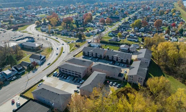 An expansive aerial view of Westmoreland Estates, showcasing its well-maintained buildings, ample parking spaces, and beautiful surrounding greenery. The complex is conveniently located near major roads, making it ideal for commuters, yet also nestled within a quiet, serene area. The abundance of trees and nearby neighborhoods adds a welcoming, suburban feel — a perfect balance of accessibility and tranquility for future residents.